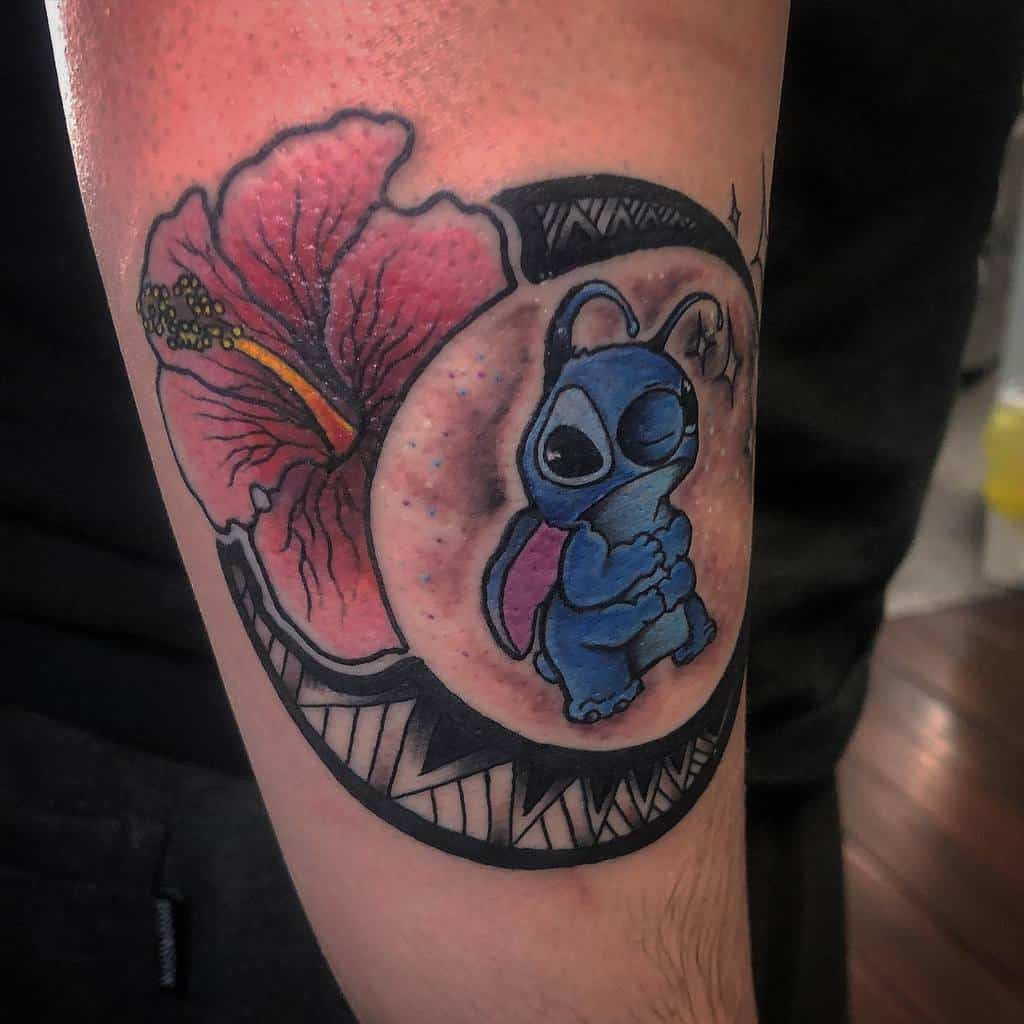 Colorful tattoo of Stitch from Lilo & Stitch inside a circular frame with a hibiscus flower, on the forearm.