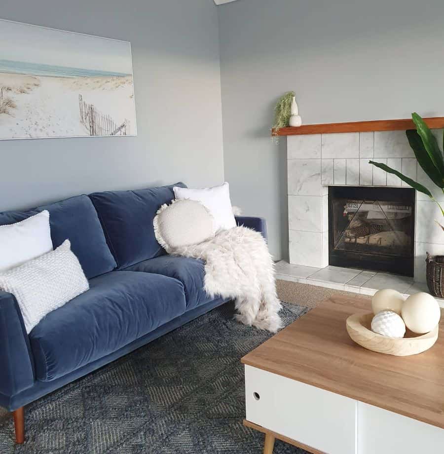 Navy blue sofa, white pillows, gray walls, and a tiled fireplace create a cozy, modern look.