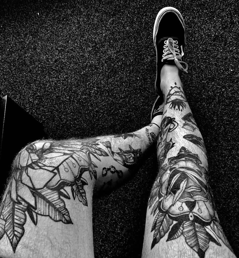 Black and white tattoo leg sleeve, featuring a mix of geometric shapes, feathers flower with leaves, and intricate designs