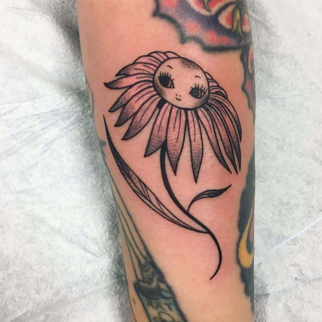 Forearm tattoo traditional color daisy with a cartoon face
