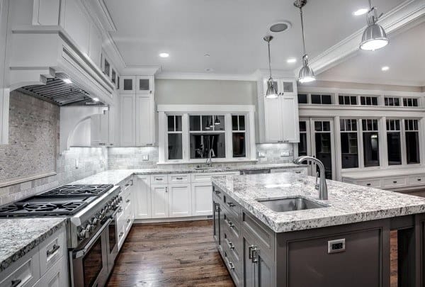 Spacious kitchen featuring a granite island countertop, white cabinetry, and a soft tile backsplash.