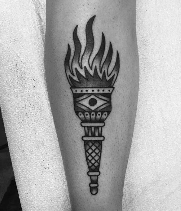 Black and grey torch tattoo with smooth shading, stylized flames, and an all-seeing eye design in the center of the handle.