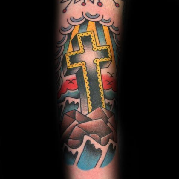 Bold cross tattoo with yellow trim rising from rocky waves, set against clouds, rays of light, and a vibrant red sky.