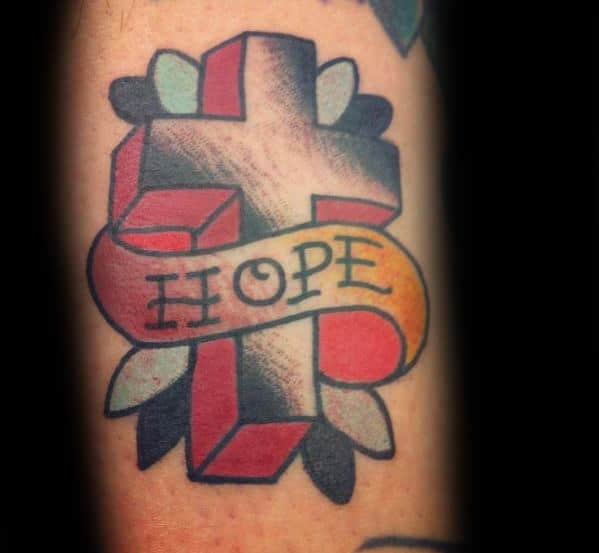 Tattoo of a cross with a banner labeled "HOPE" and leaf designs