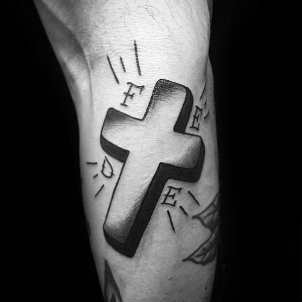 Tattoo of a shaded 3D cross with letters "F," "R," "E," and "E" around it on an arm