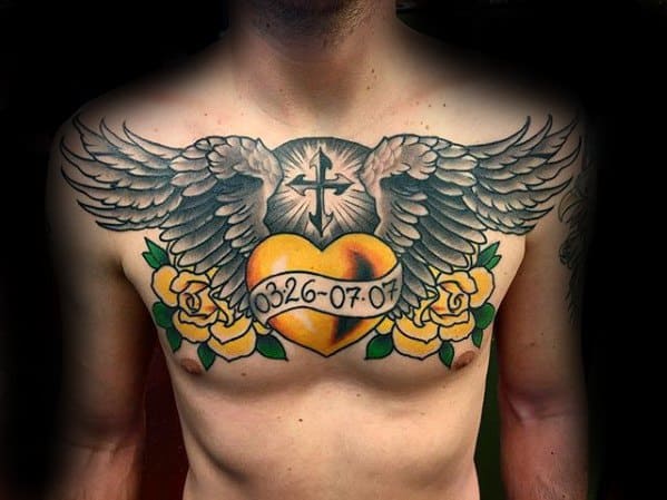 Chest tattoo featuring a winged golden heart with the dates "03·26–07·07," flanked by yellow roses and a radiant cross above.
