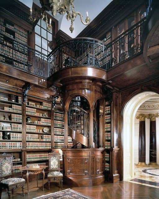 Luxurious library with wooden shelves, spiral staircase, and elegant seating area under ornate chandelier