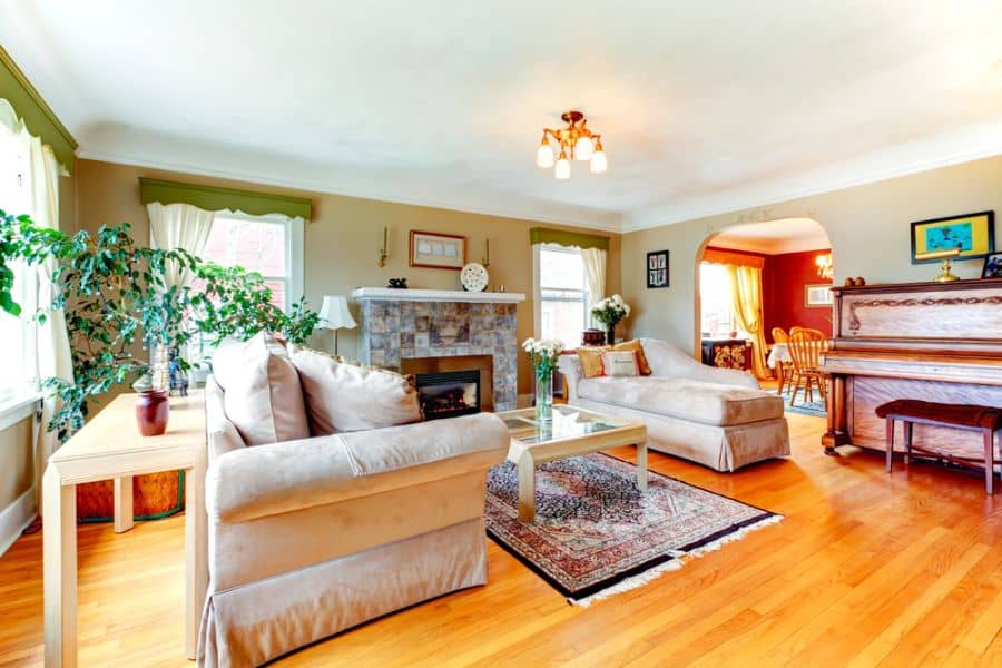 traditional family room floorboards gray couch fireplace piano 