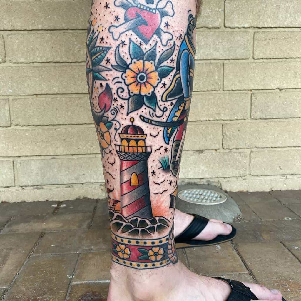 Vibrant tattoo leg sleeve featuring a lighthouse, colorful flowers, a heart and bones design, and a vintage-style sailor figure