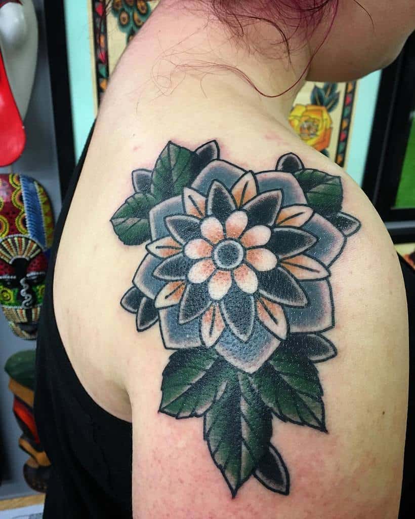 A detailed floral tattoo with leaves is on the shoulder