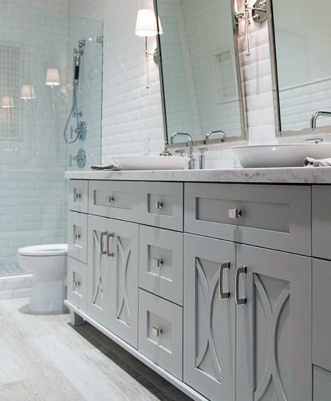 Cottage-style grey double vanity with marble countertop and subway tile shower backdrop.