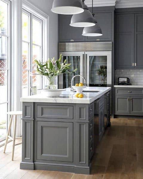 Traditional grey kitchen with paneled island, pendant lighting, and stainless steel appliances.
