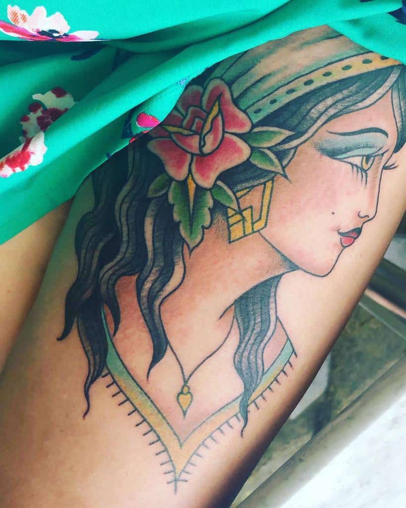 Tattoo of a gypsy woman with a flower in her hair and vibrant, colorful details adorning the skin