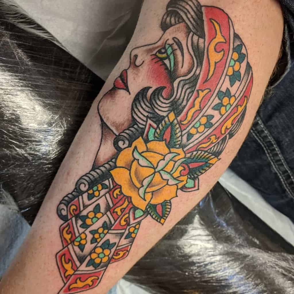 Leg tattoo of a gypsy woman in a headscarf, elegantly adorned with a vibrant yellow rose