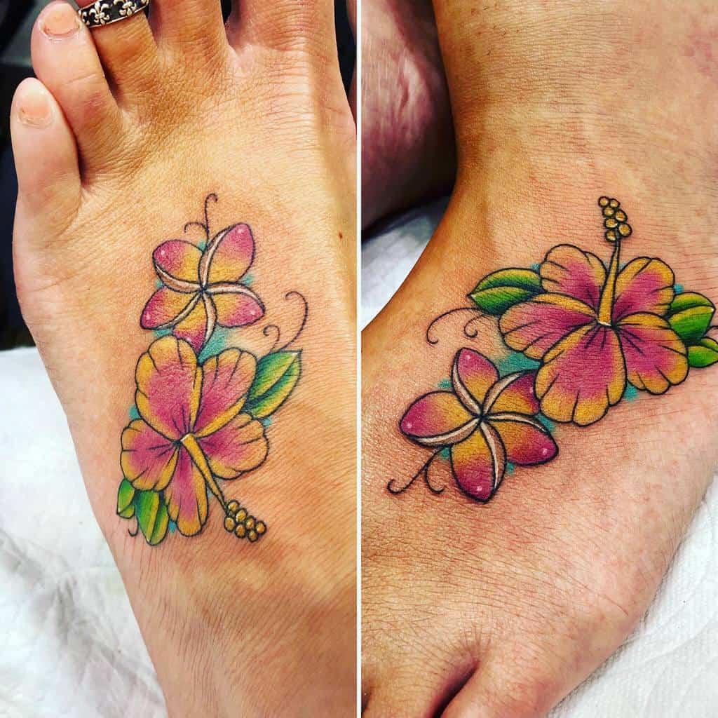 Colorful foot tattoos featuring hibiscus and plumeria flowers in soft pink, yellow, and green shades with delicate outlines