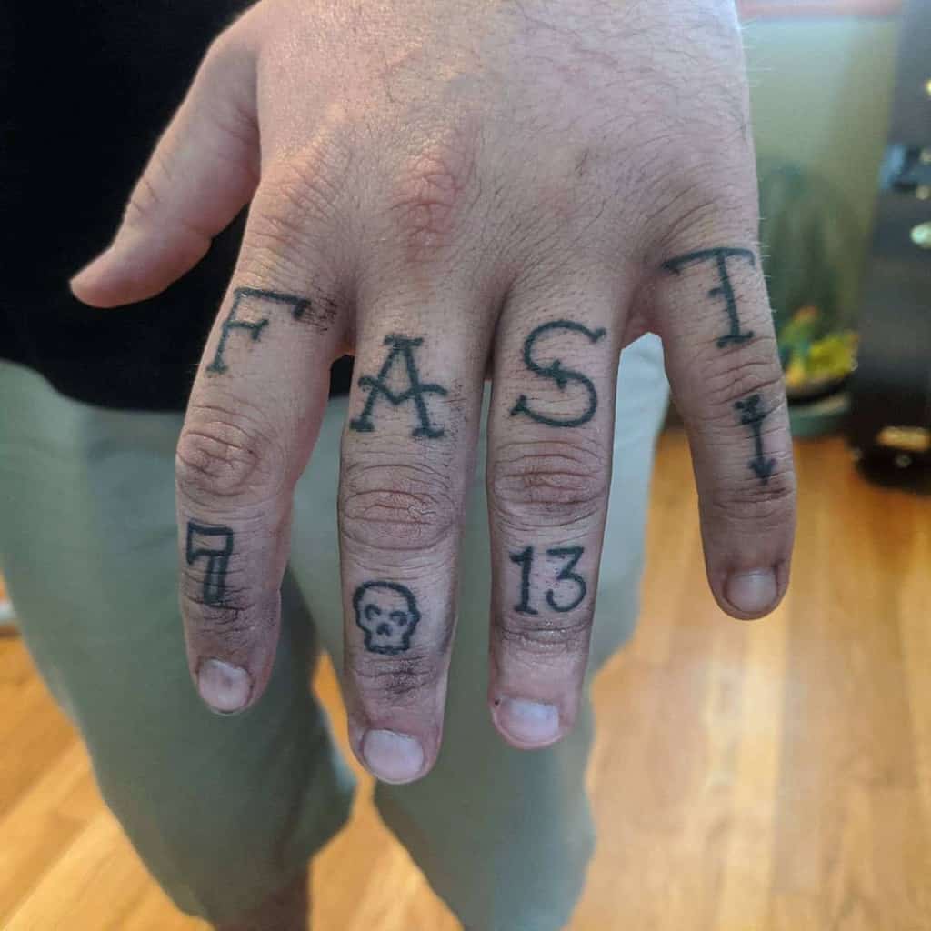 Hand with "FAST," a skull, and numbers "7" and "13" tattooed on fingers