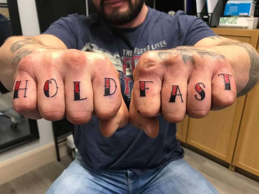 Man displaying "HOLD FAST" tattoos on knuckles