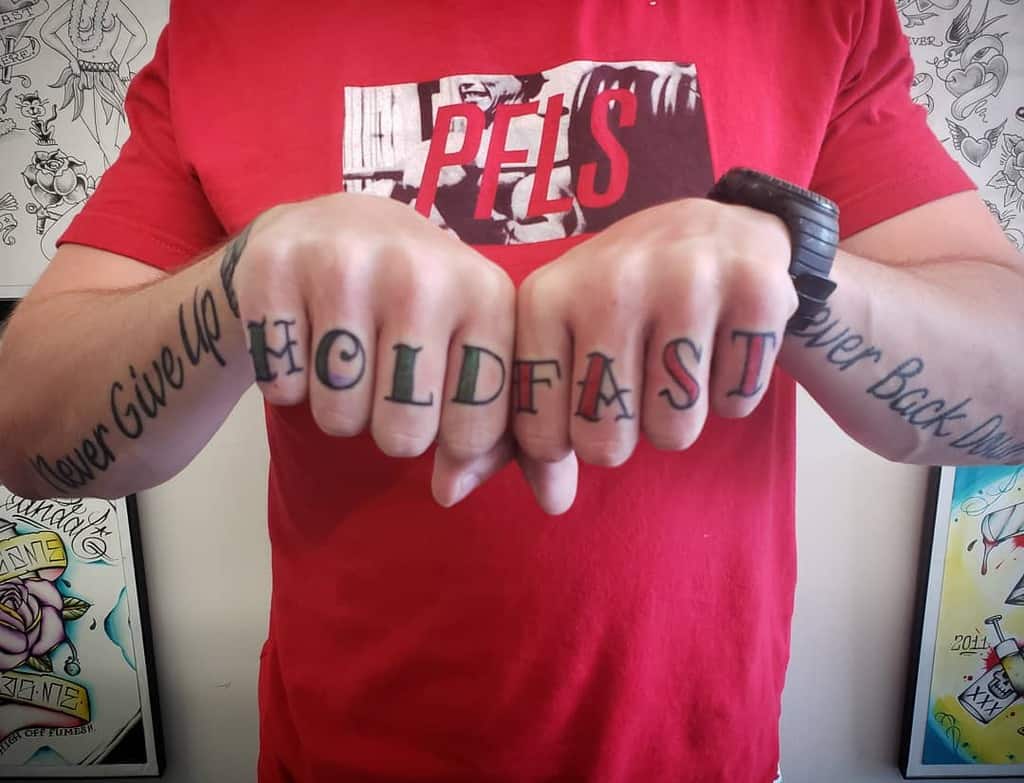 Man with "HOLD FAST" tattooed on knuckles