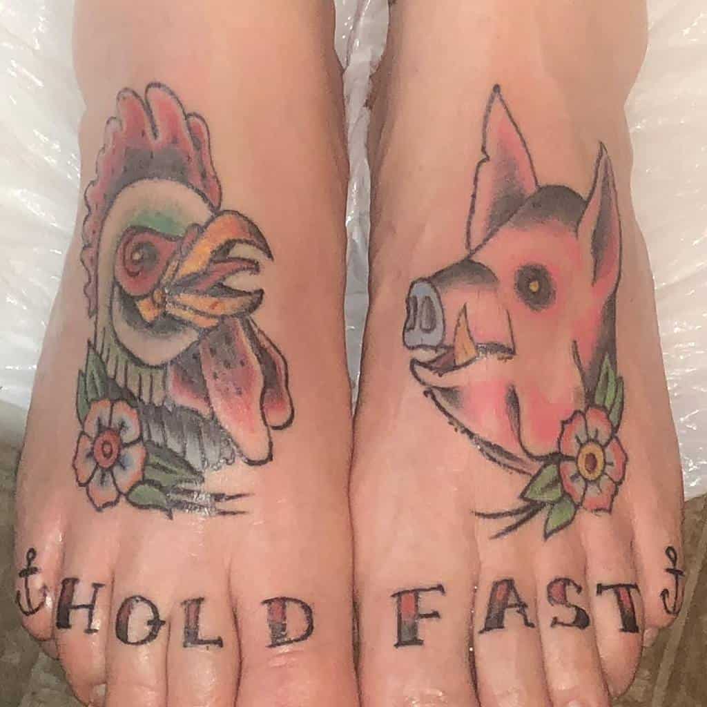 Two feet with a rooster tattoo on the left and a pig tattoo on the right, "HOLD FAST" below