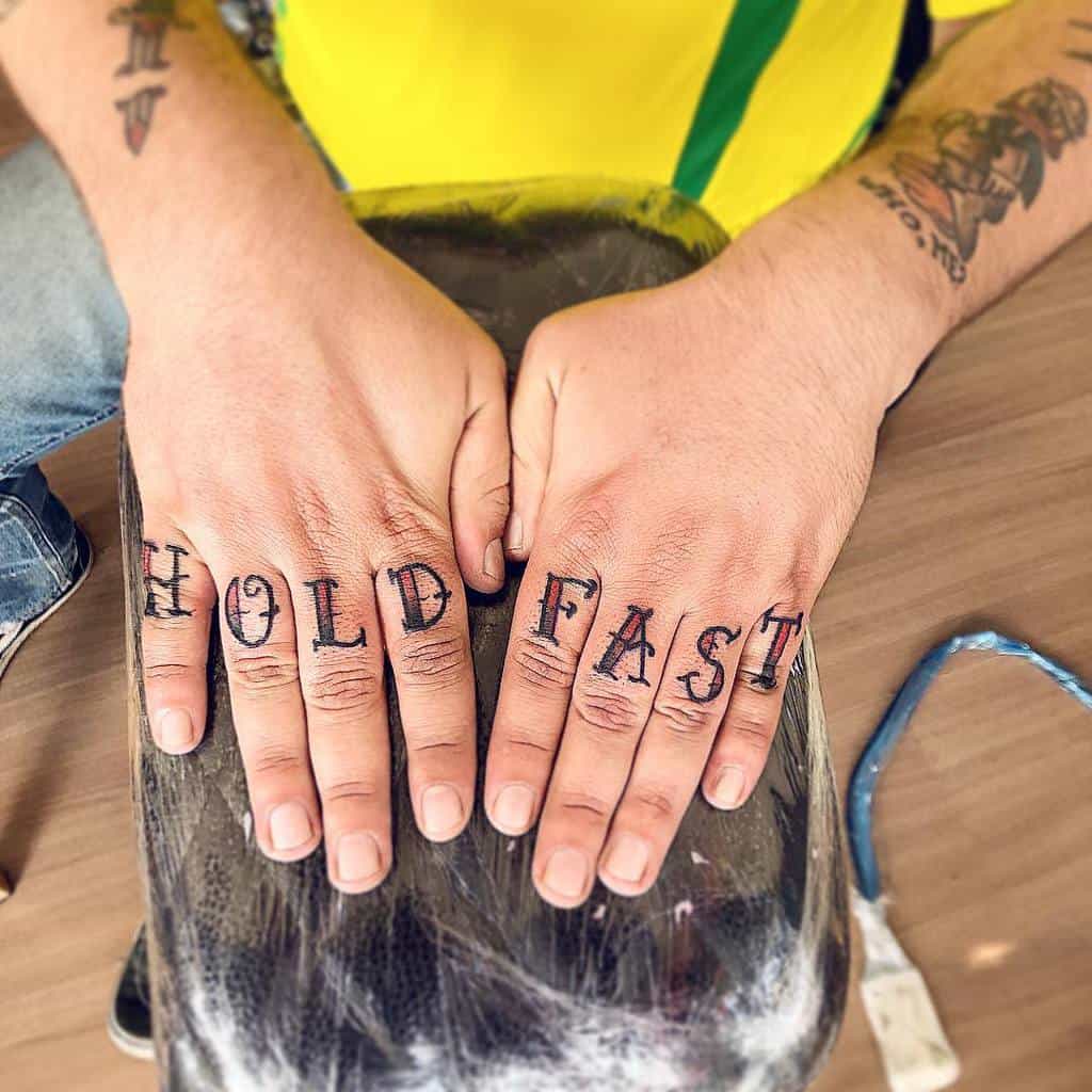 Hands with "HOLD FAST" knuckle tattoos
