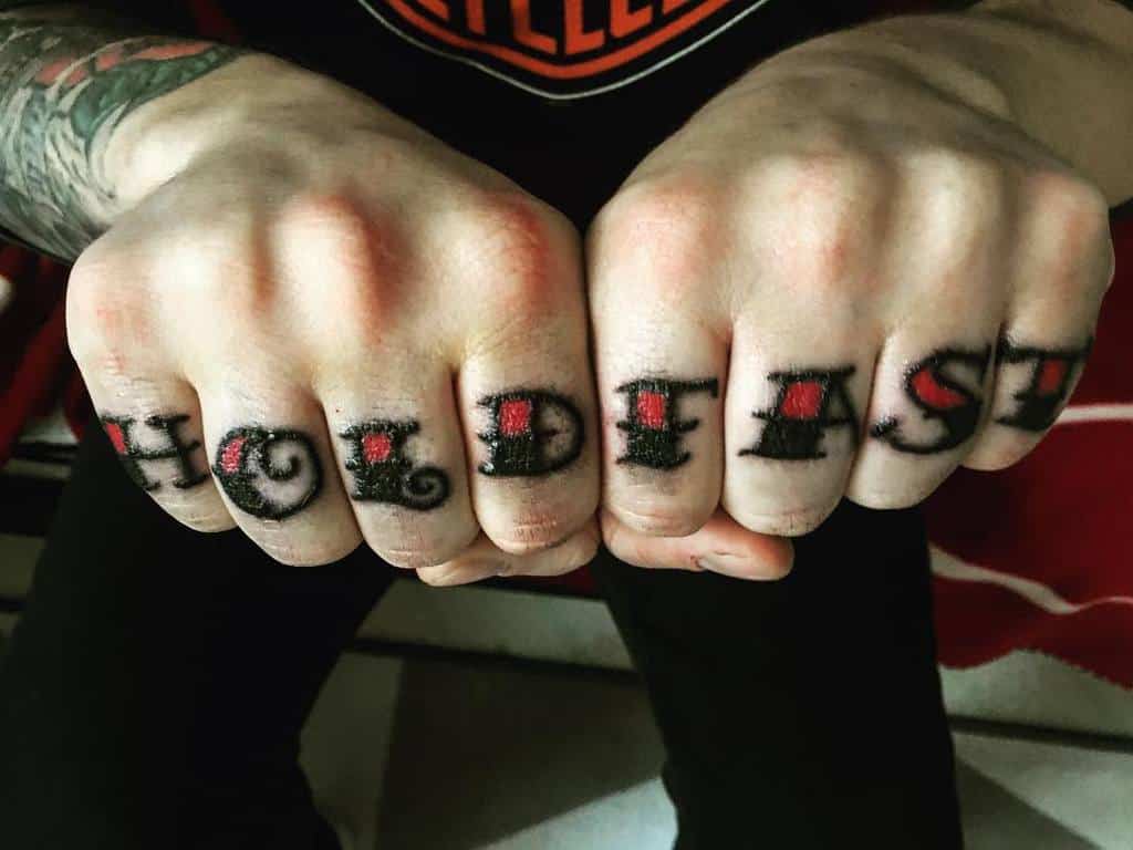 Knuckles with tattoos spelling "HOLD FAST" in bold letters