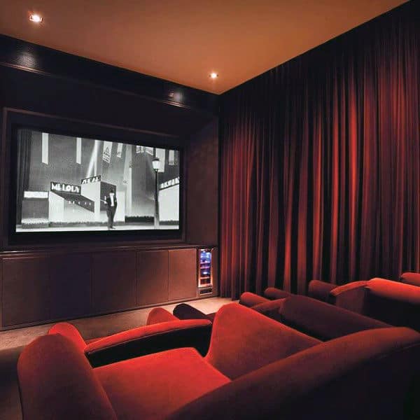 Home theater with red seats and a large screen displaying a black and white film