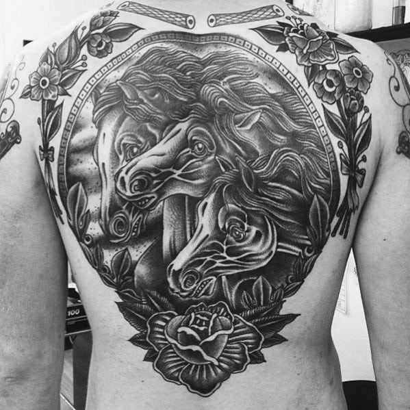 Intricate full back tattoo in black and grey featuring three realistic horse heads framed by floral designs, rope border, and a rose.