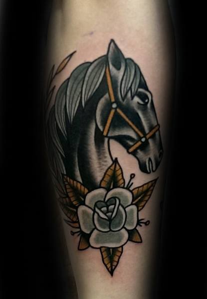 Traditional tattoo of a black horse head with flowing mane, golden harness, and a white rose with brown leaves below.