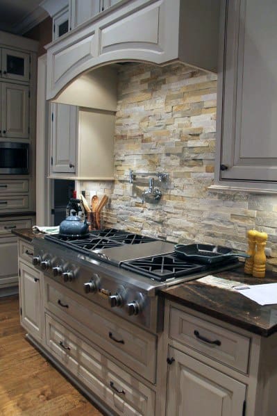 Traditional kitchen with warm-toned stone backsplash, custom cabinetry, and a professional-grade stovetop, creating a cozy yet elegant ambiance