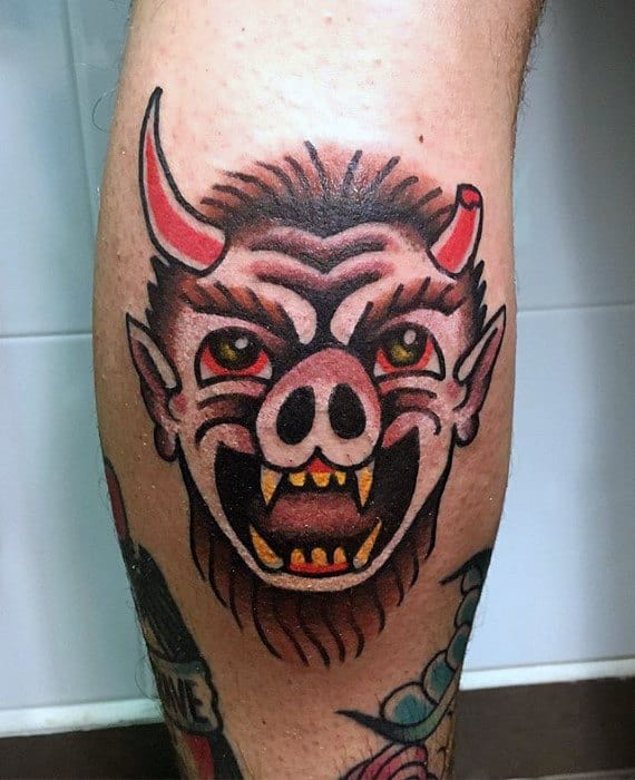 Traditional Krampus tattoo with a pig-like snout, red horns, fierce eyes, sharp yellow teeth, and a bold black and red color scheme.