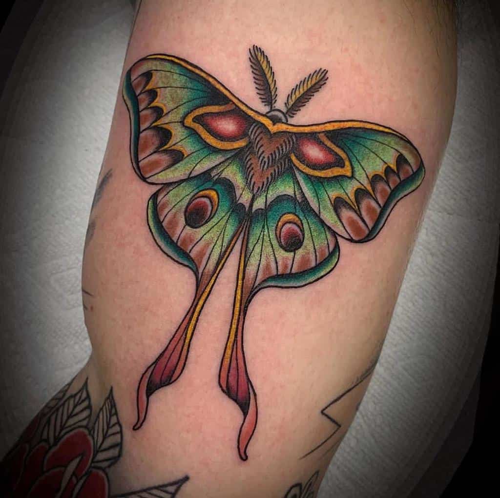 A colorful Luna Moth tattoo with vibrant greens, reds, and yellows, featuring intricate details and patterns
