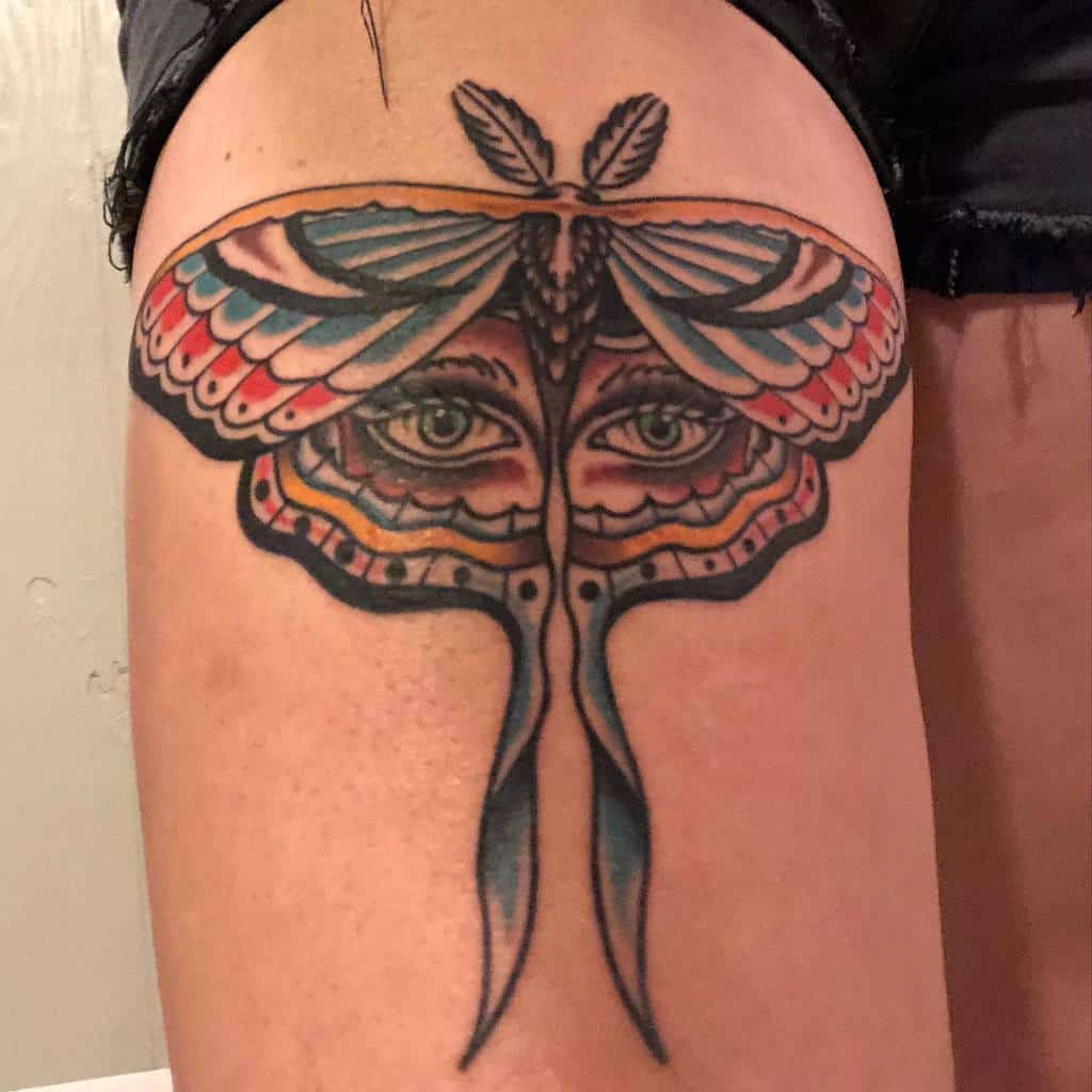 A colorful tattoo of a Luna Moth with detailed eyes in the center of the wings, featuring bright blues, reds, and yellows