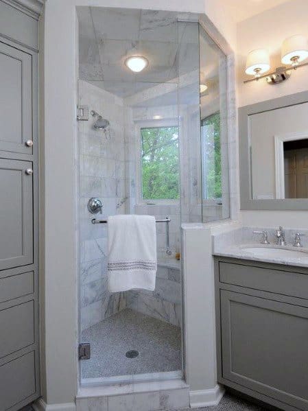 Compact bathroom with a glass shower tucked in the corner, gray cabinets, and a white towel hanging inside