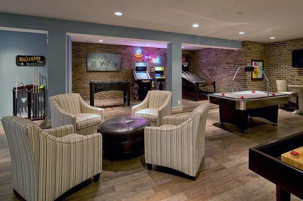 Game room with striped chairs, air hockey table, arcade games, and exposed brick walls