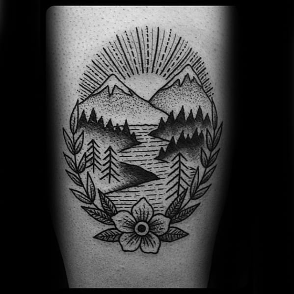 Blackwork tattoo of mountains, a winding river, and pine trees, framed with laurel leaves and a central flower at the bottom.