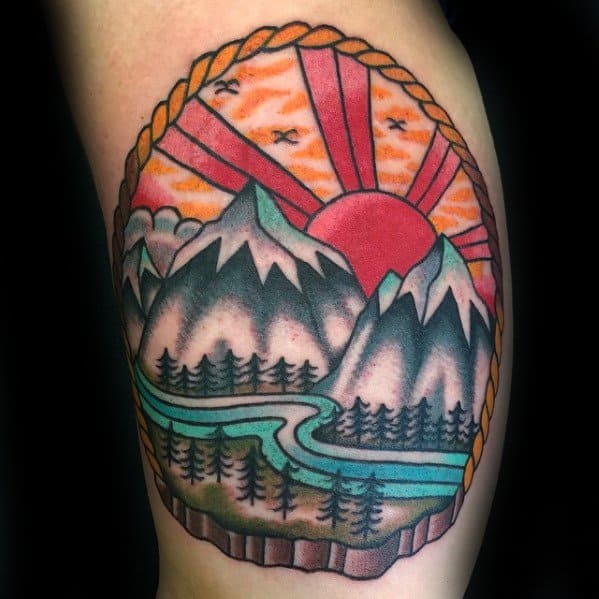 Vibrant mountain tattoo with snowy peaks, winding river, pine trees, and a bold red sun, framed by a rope border and flying birds.
