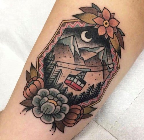Geometric tattoo of a night mountain scene with a cable car, pine trees, crescent moon, and floral accents framing the design.