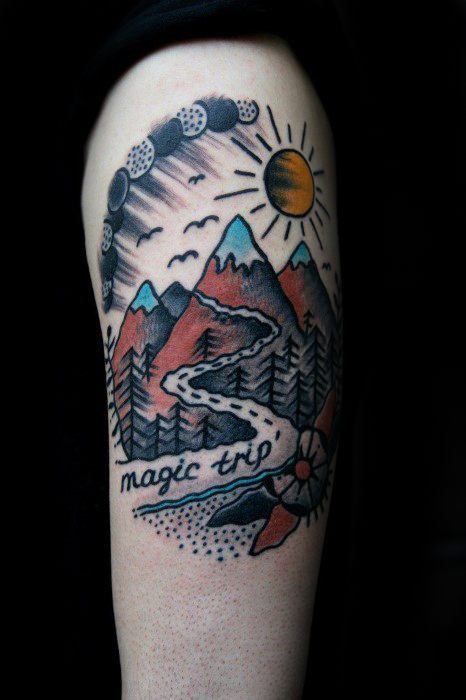 Colorful mountain tattoo with a winding path, sun, moon phases, compass, pine trees, and the phrase “magic trip” written across.