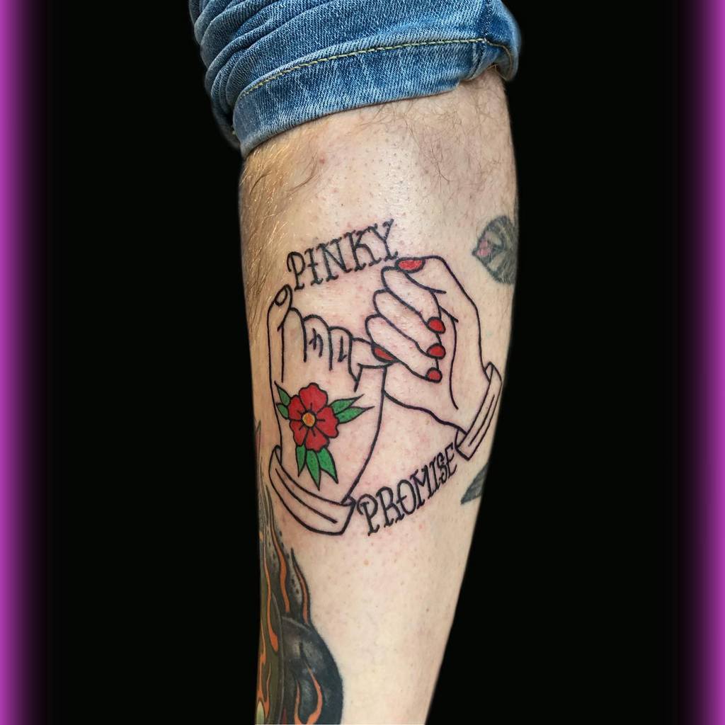 Tattoo of two hands making a pinky promise with the text "Pinky Promise" and a small flower beneath them