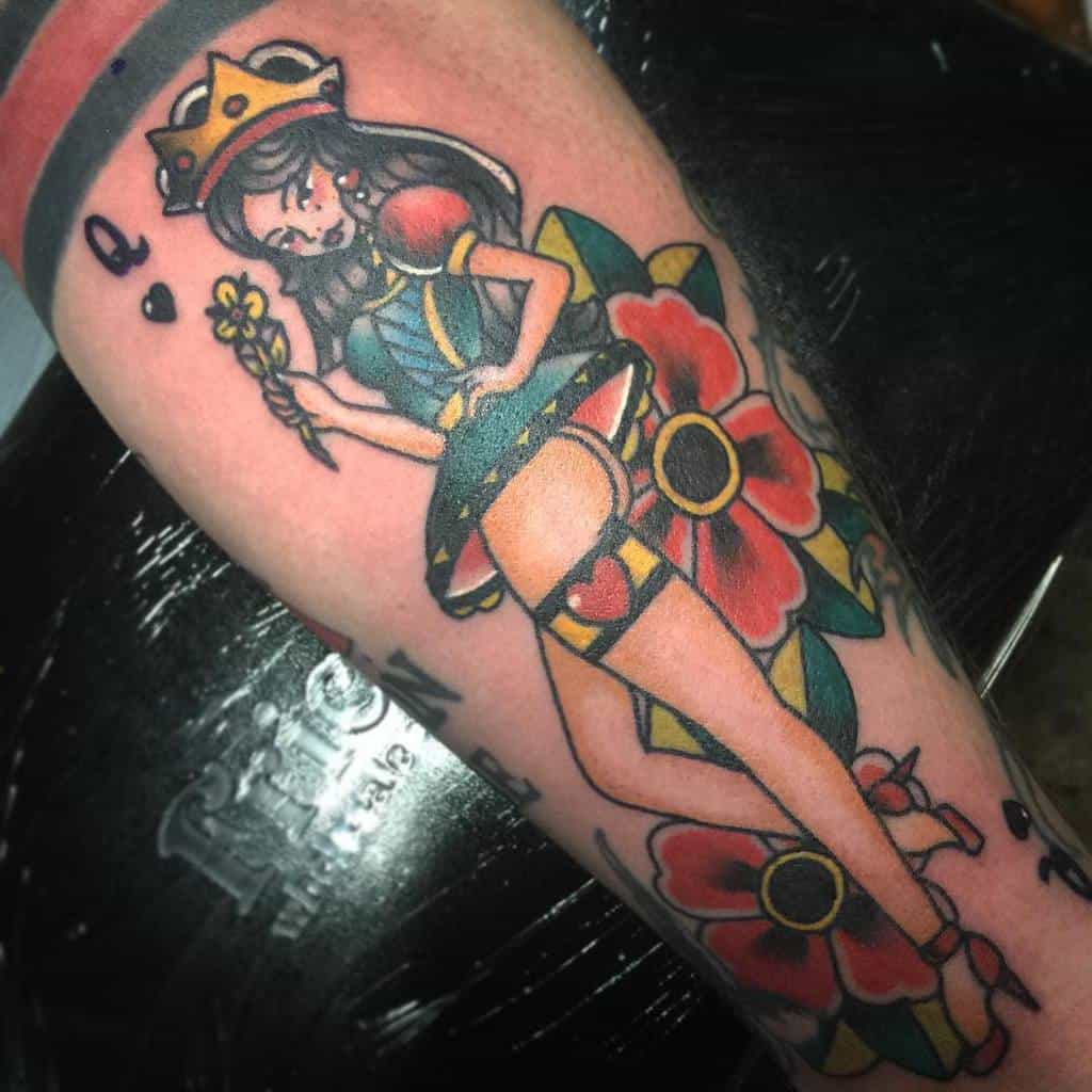 Bold traditional Queen of Hearts tattoo featuring vivid colors, a playful design, and floral accents surrounding the figure