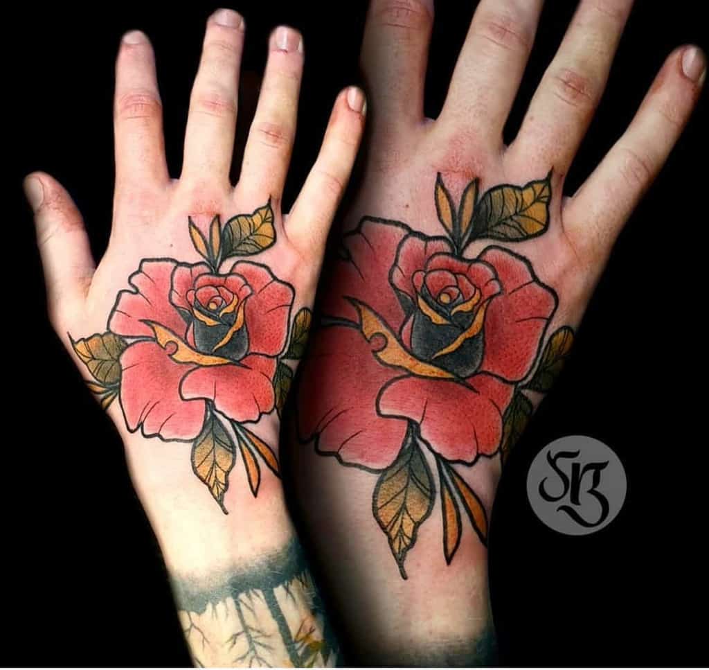 Two hands adorned with matching rose tattoos, elegantly intertwined amidst green leaves