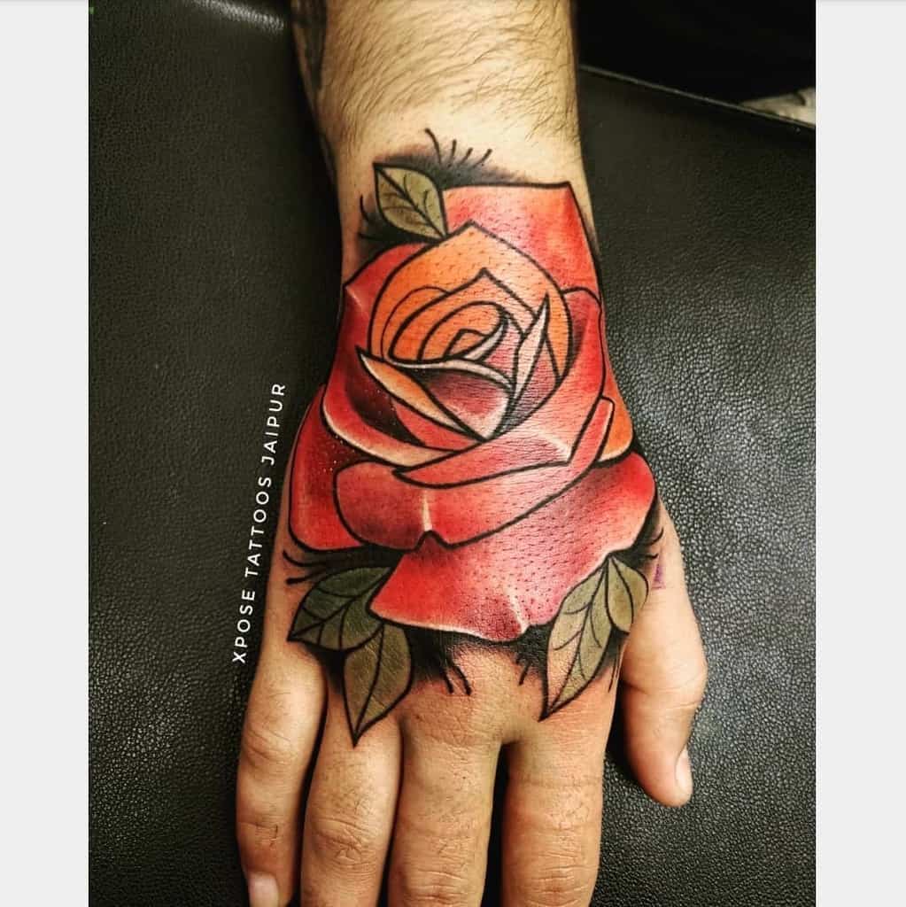 Tattoo of a red rose with green leaves on the back of a hand