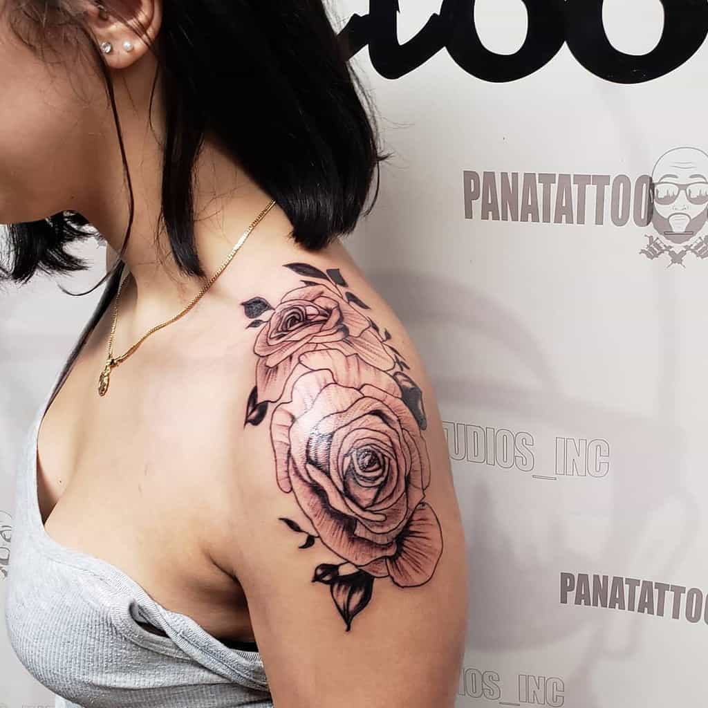 A traditional black and grey rose tattoo on the shoulder, featuring two detailed roses with soft shading and bold outlines