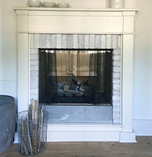 Traditional gas fireplace with a white brick surround, a metal mesh screen, and a classic mantel.