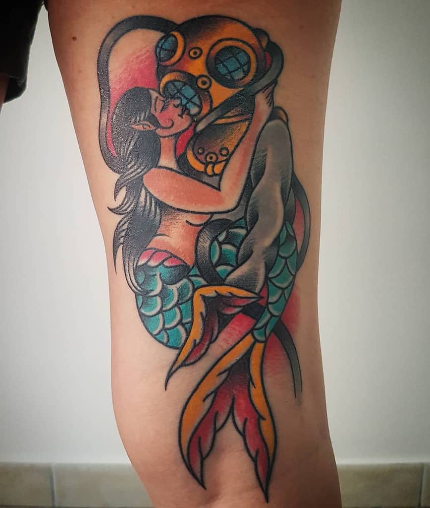 Classic tattoo of a siren embracing a deep-sea diver, featuring bold colors, vintage diving helmet, and flowing mermaid details