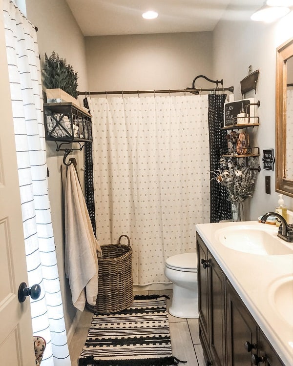 Cozy farmhouse bathroom with a shower curtain, wicker basket, towel rack, sink, and decorative plants