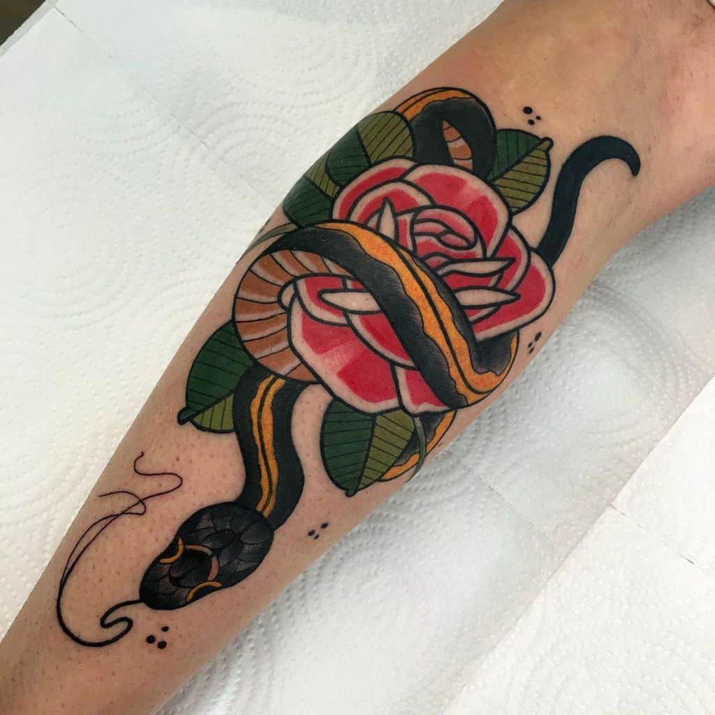 A tattoo of a snake coiled around a red rose with green leaves on a forearm