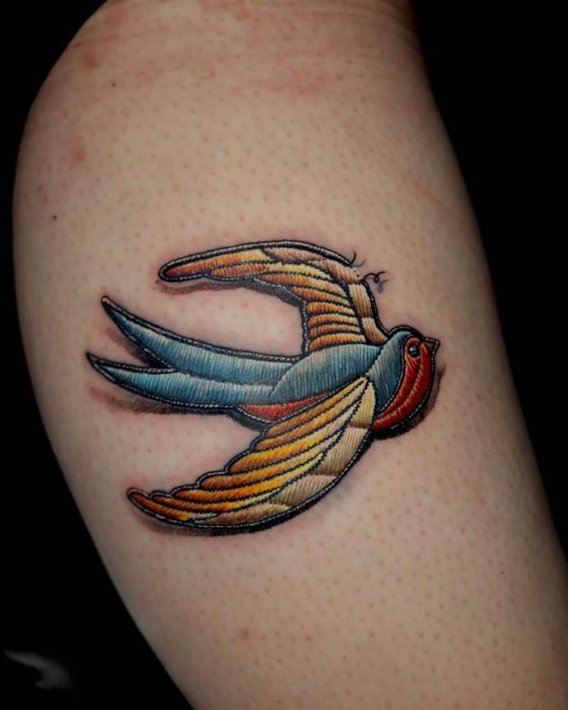 Textile-effect tattoo of a soaring bird, blending smooth stitch patterns with a handcrafted embroidered design.