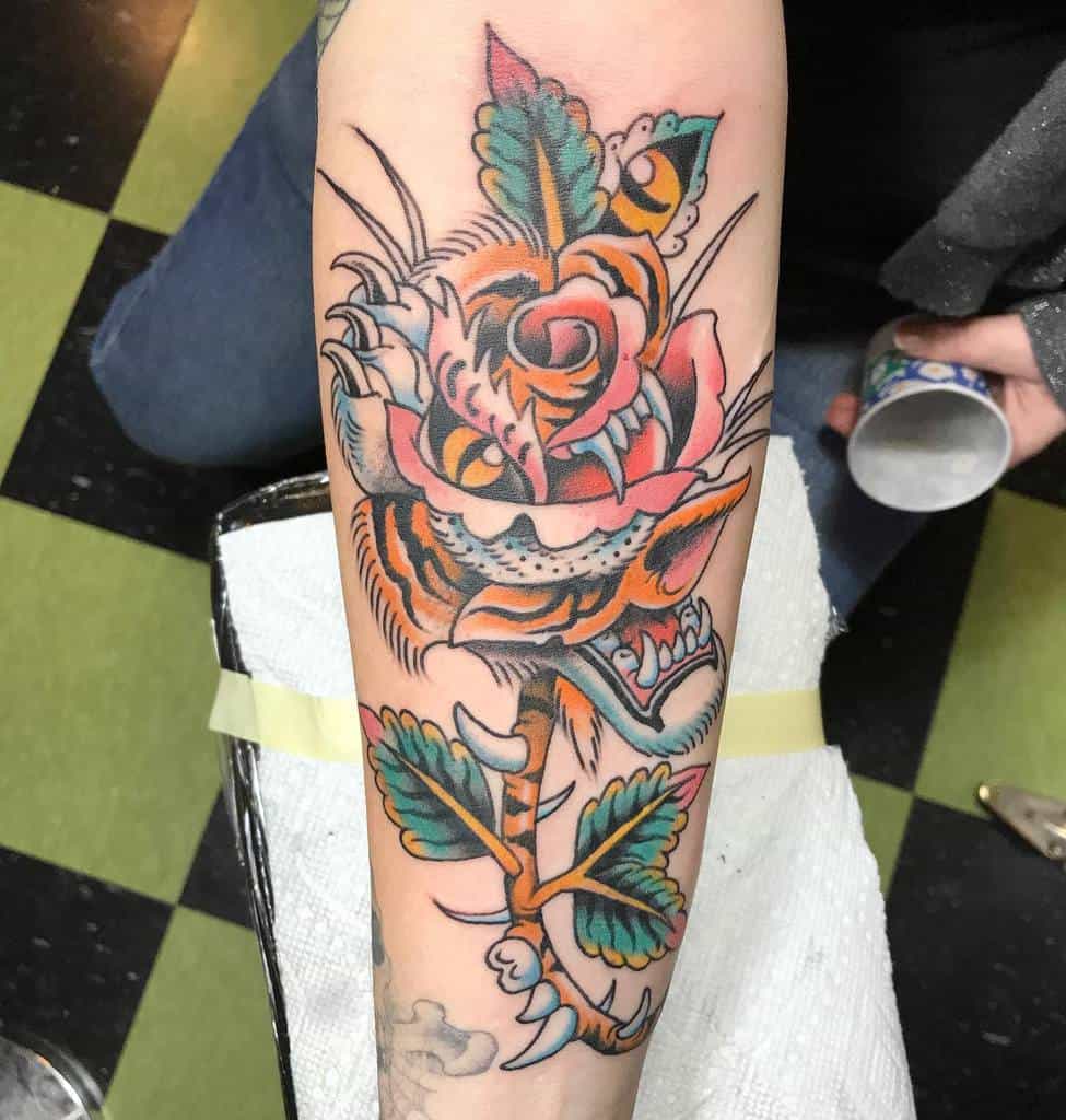 A vibrant tattoo featuring a majestic tiger intertwined with a brilliant rose graces the forearm