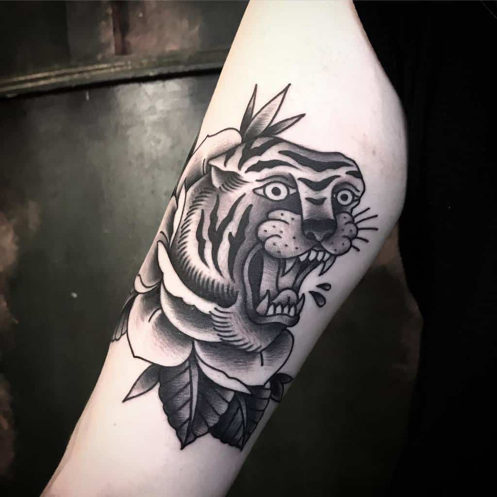 A tattoo of a fiercely snarling tiger's head elegantly blended with a delicate rose graces the forearm